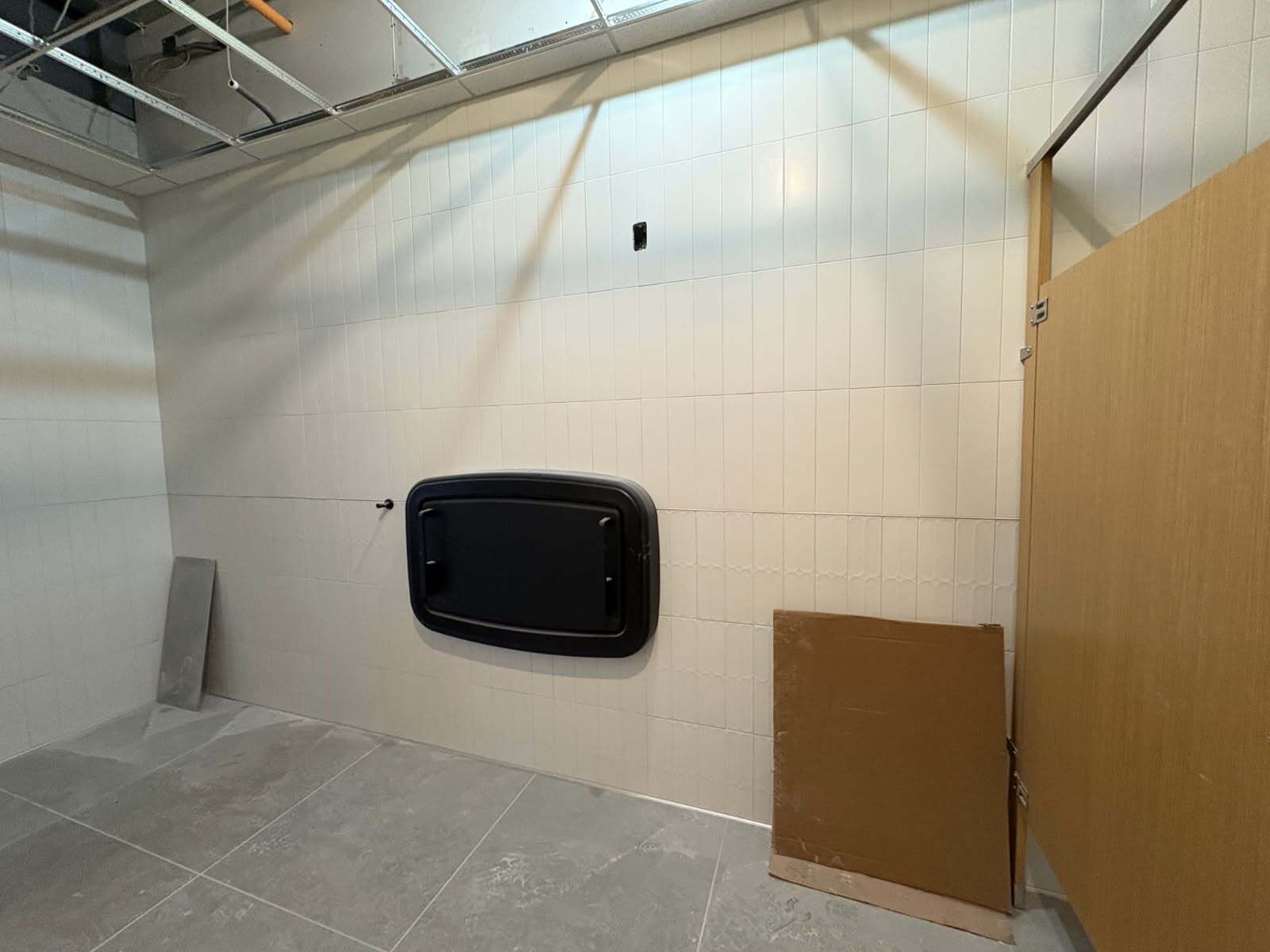 Interior of a restroom under construction, with a changing table and stall door.