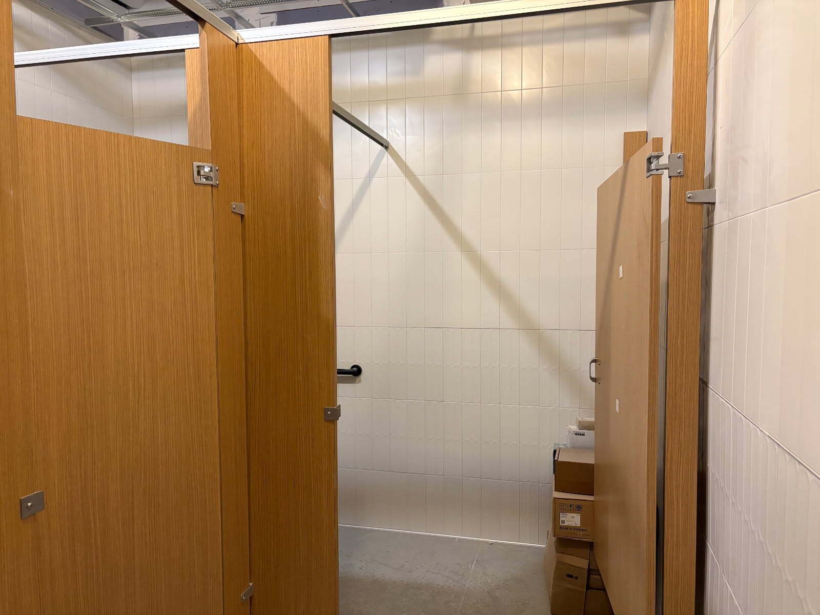Bathroom stalls with wooden doors and white walls.