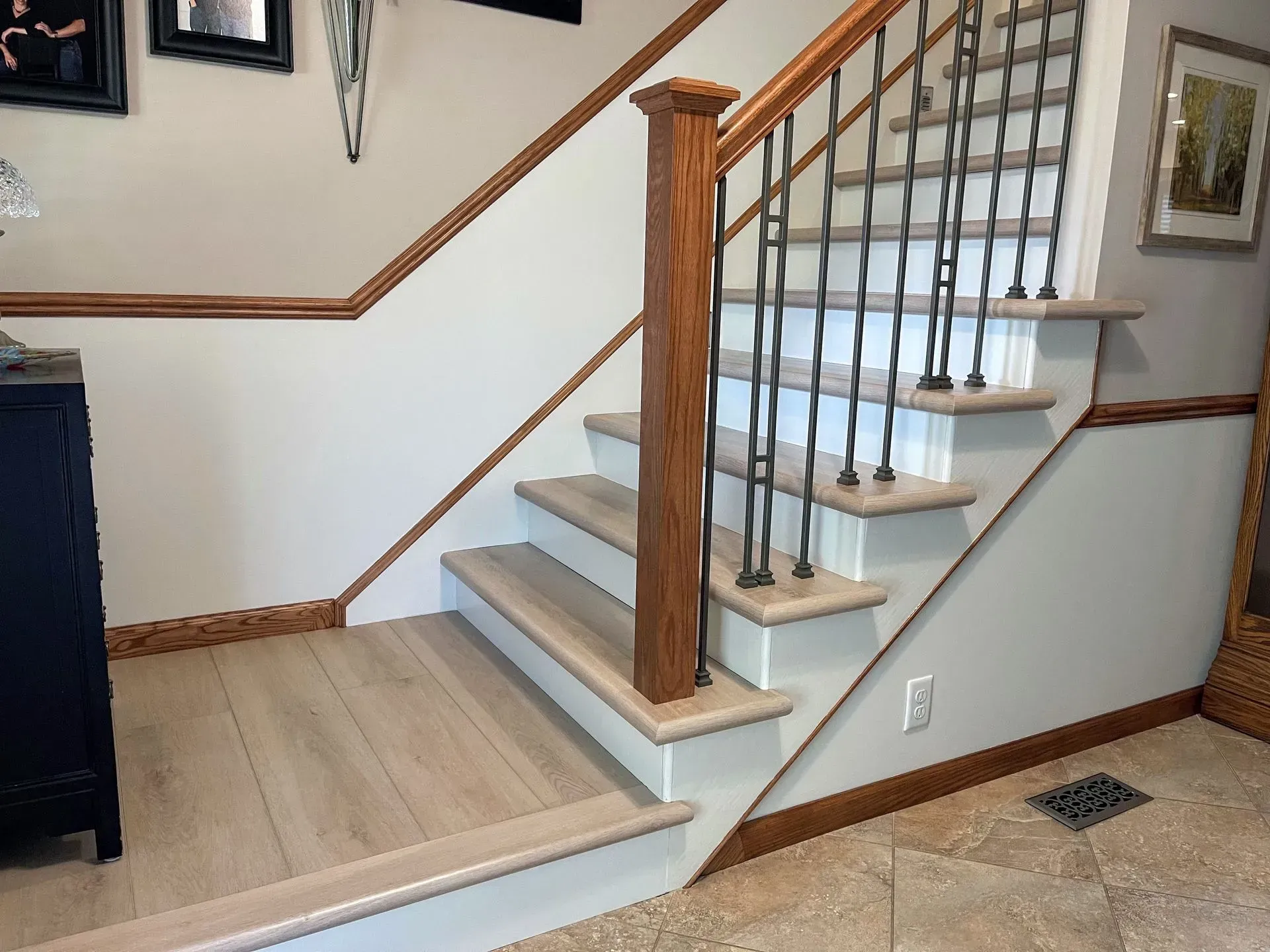 Staircase with light wood steps, white risers, dark railing, and wood trim.