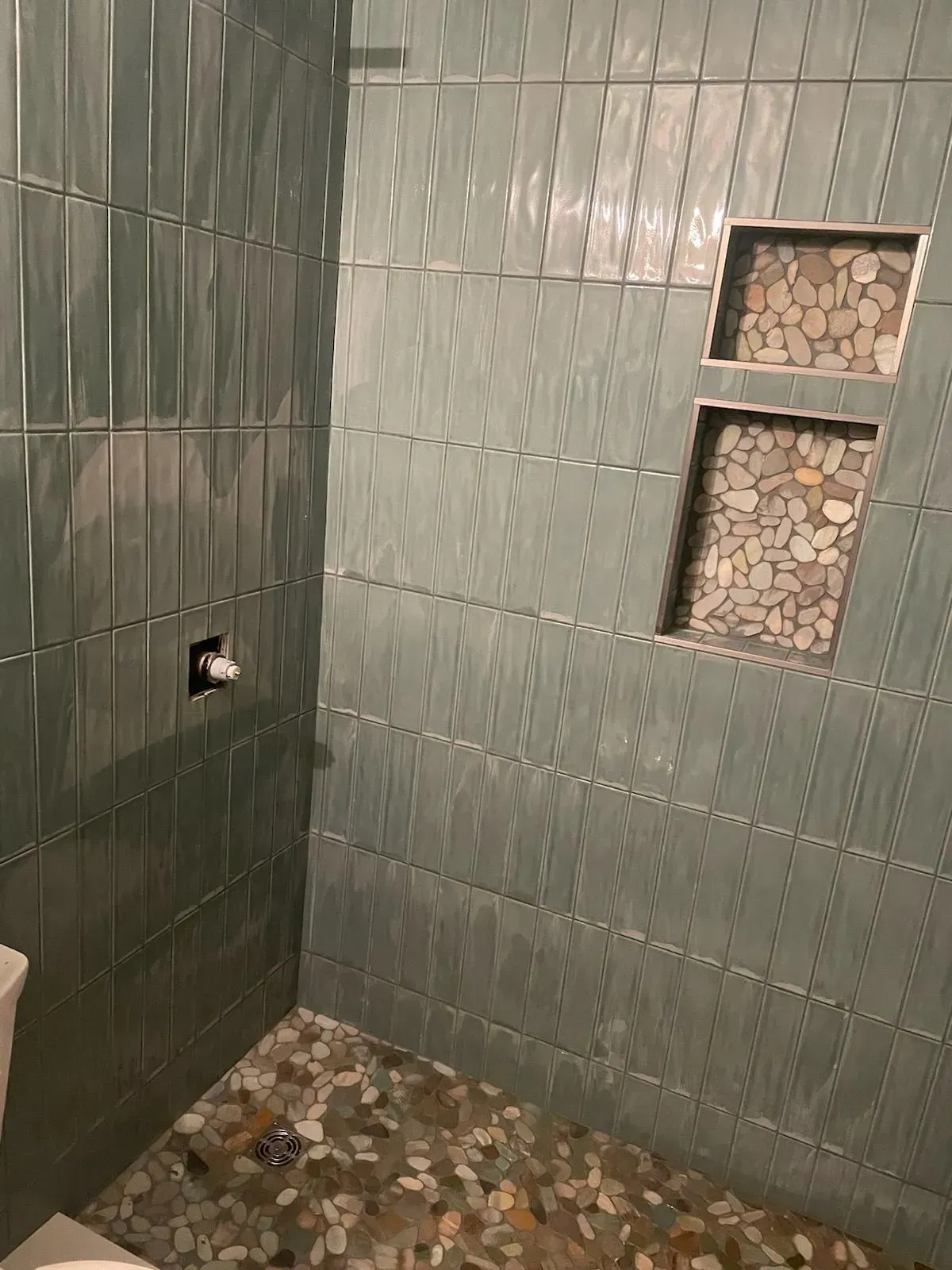 Aqua-tiled shower with pebble-lined shelves and floor.