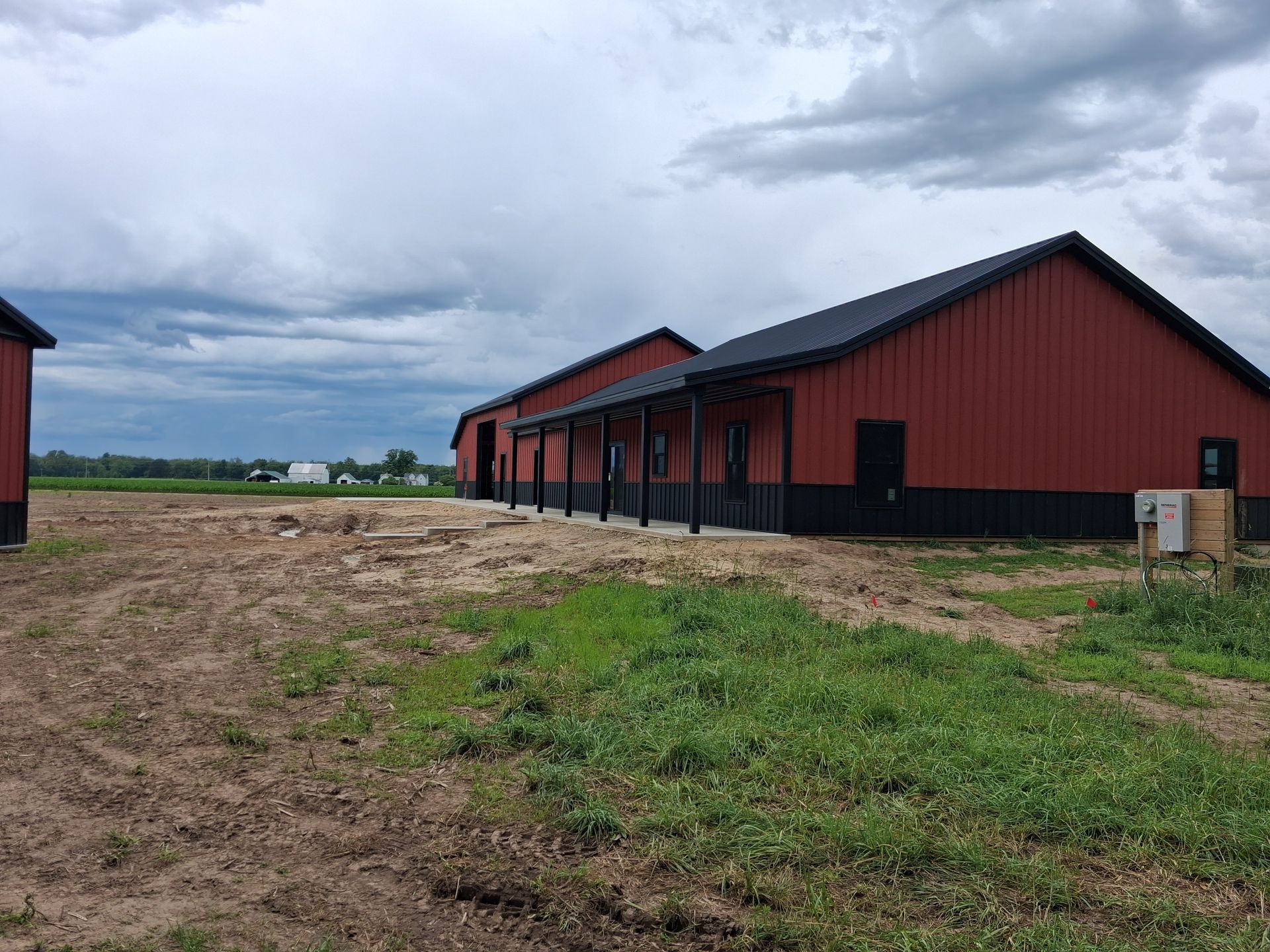 Row of red barns on a muddy farm under a cloudy sky