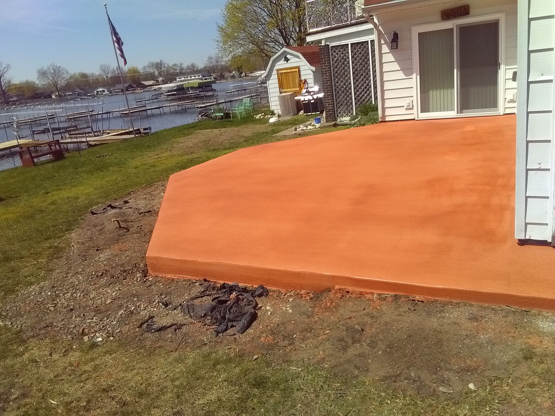 Orange concrete patio beside a house overlooking a grassy lakeside yard
