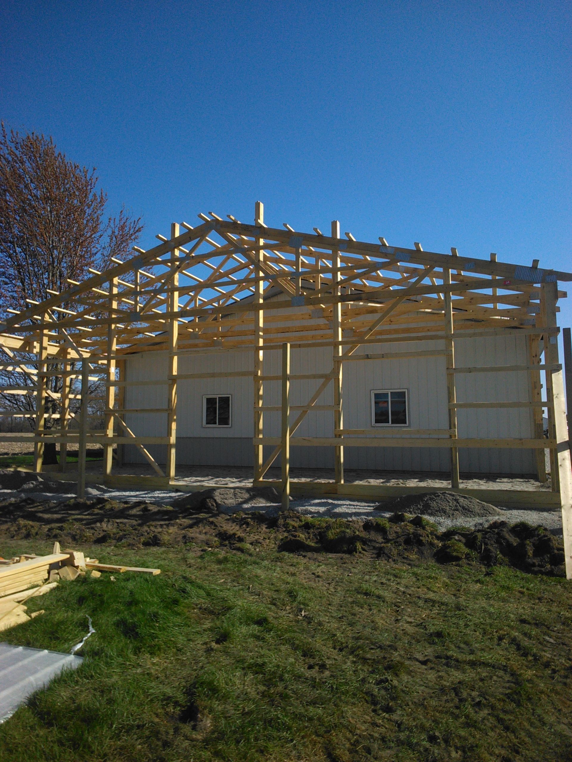 Partially built house with wooden roof framing against a clear blue sky