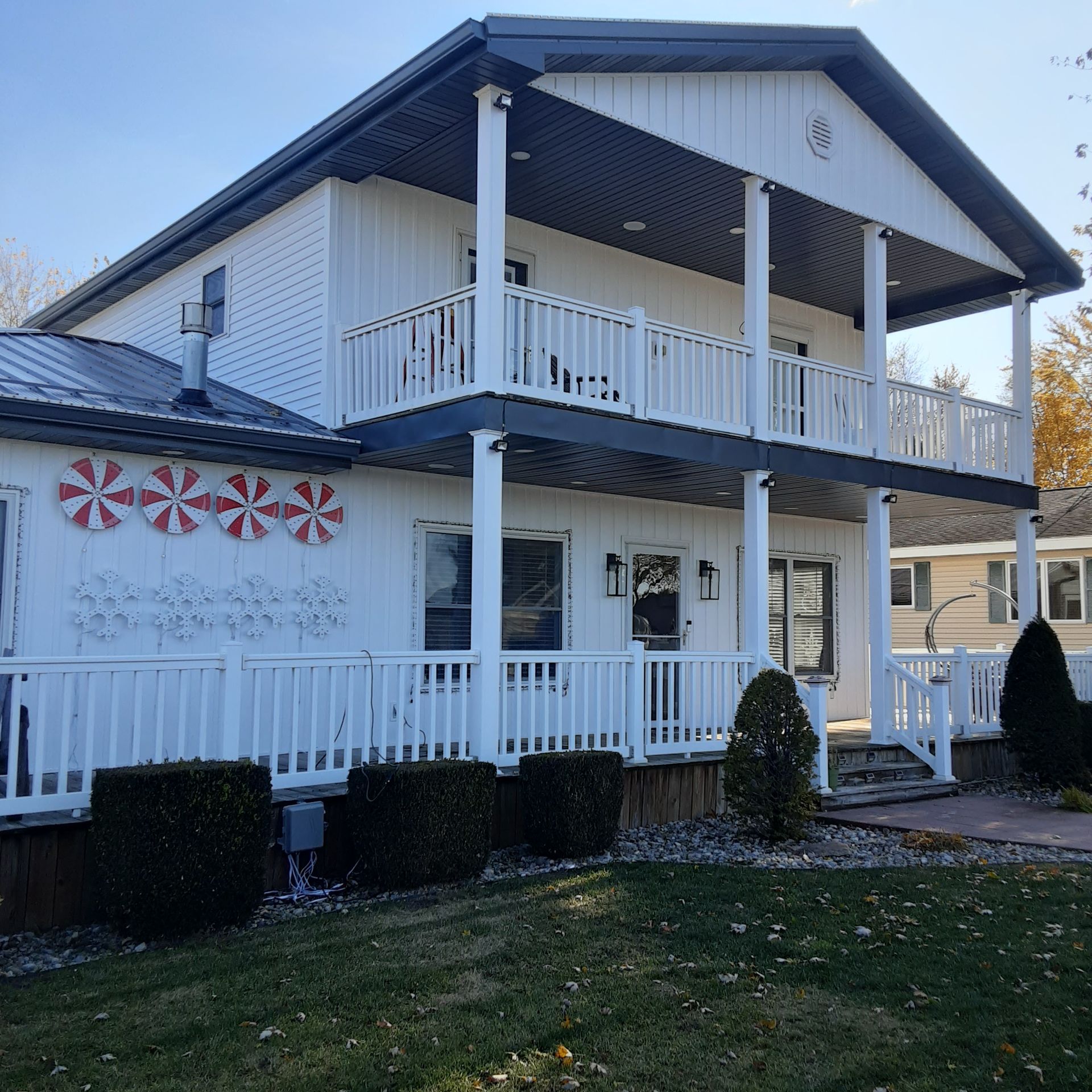 White two-story house with porch, railings, and holiday wreath decorations in front yard