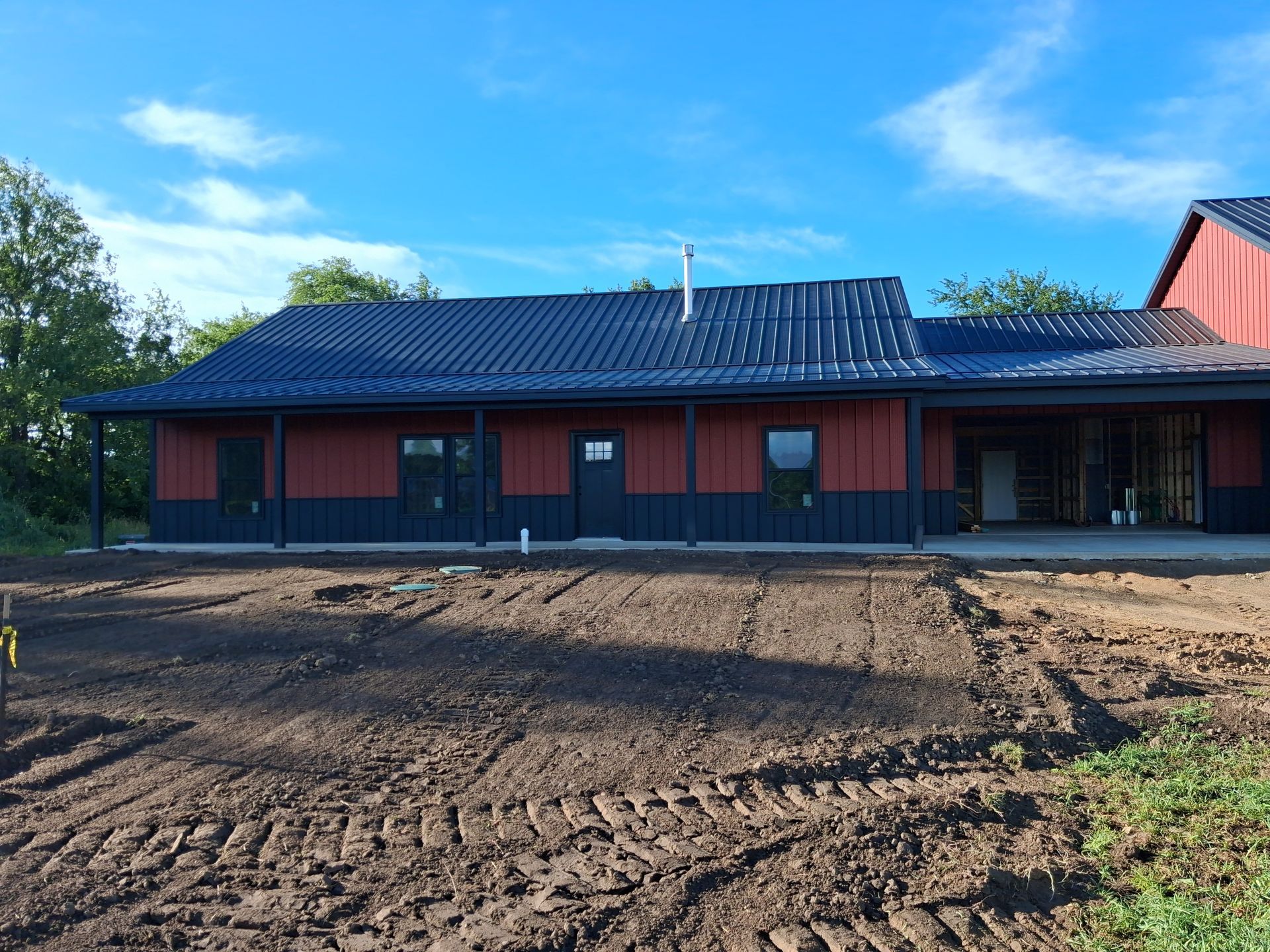 Single-story red building with blue roof on a dirt lot under a clear sky