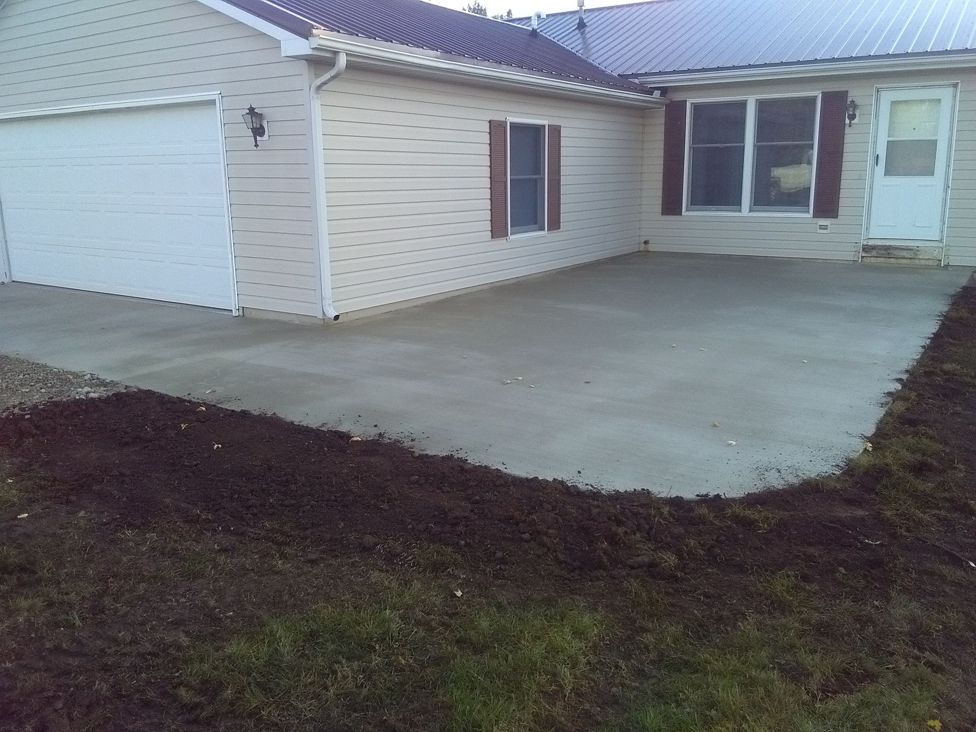 Single-story house with a new concrete driveway and dark soil border in front