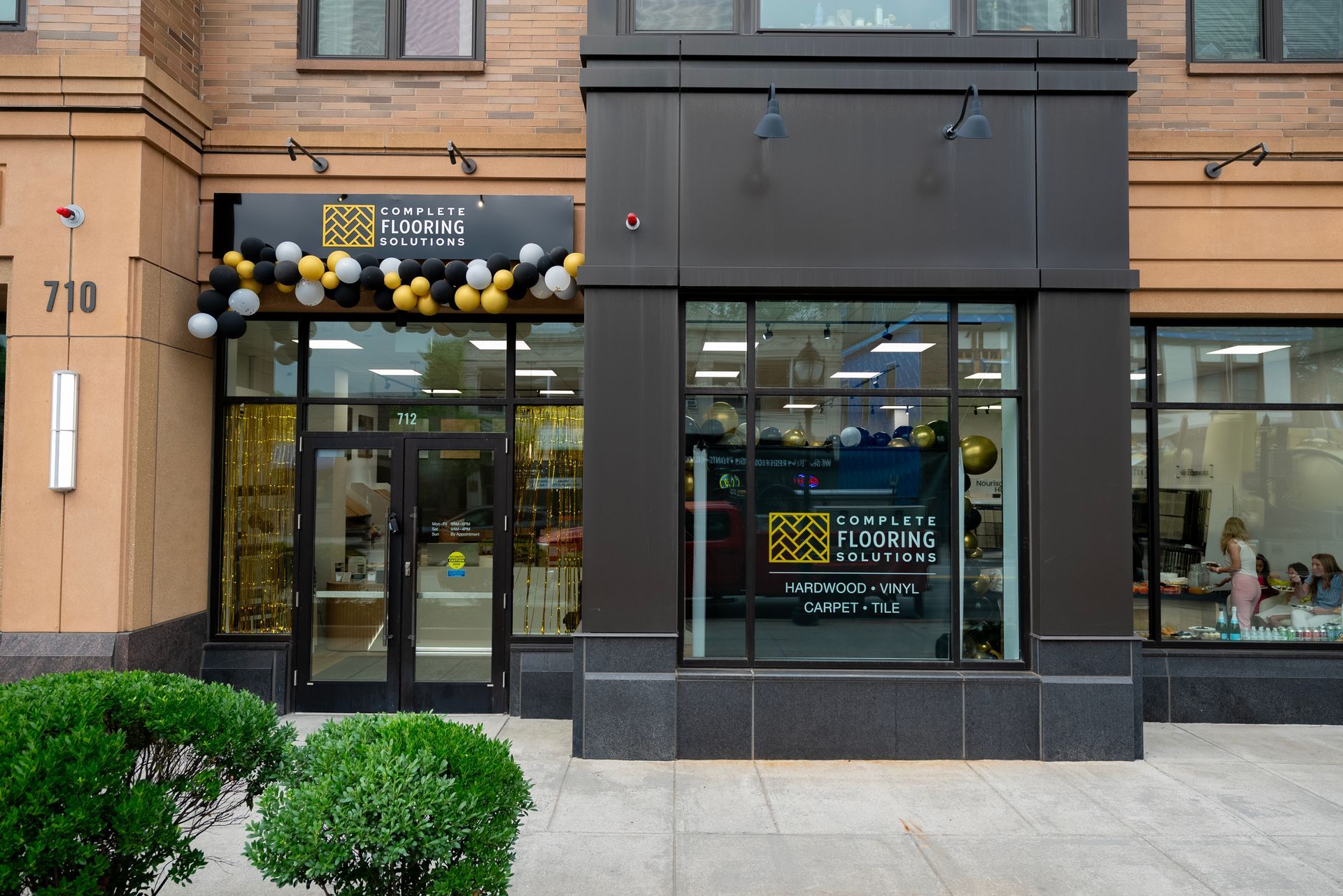 Storefront with dark facade, glass door, and large windows under a row of hanging lights
