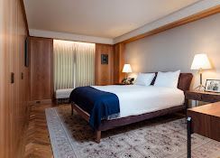 Cozy bedroom with a large bed, wooden furniture, bedside lamps, and a window with curtains