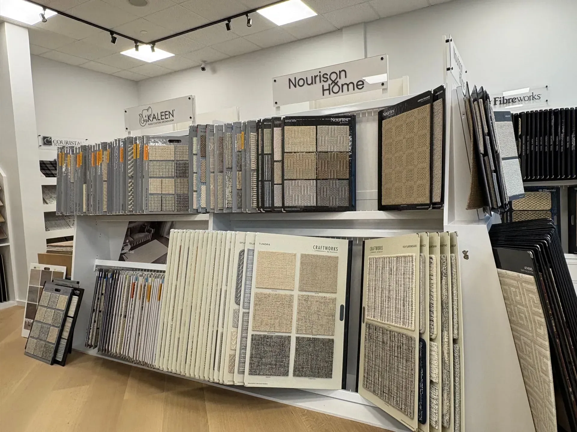 Wallpaper display wall in a store, with sample books and panels on shelves.