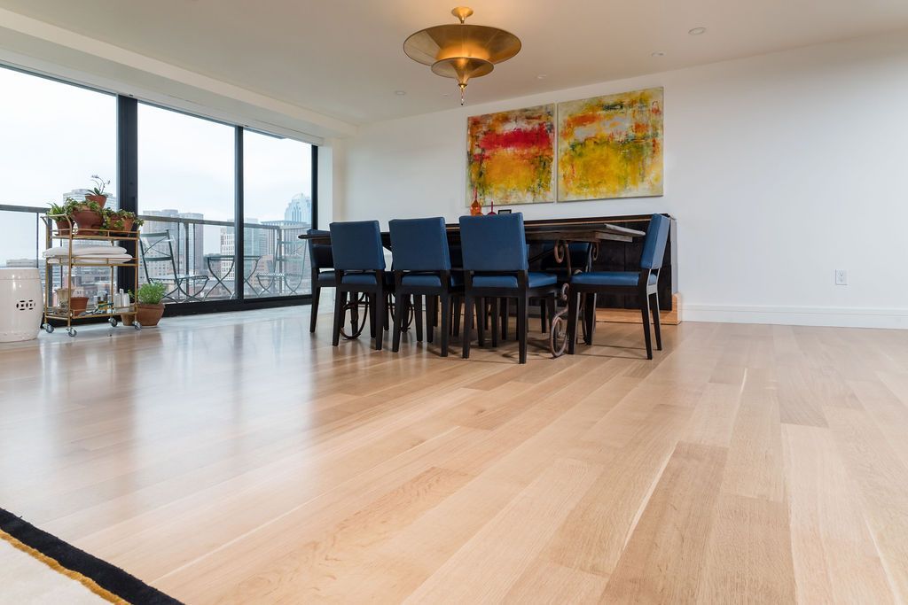 Modern dining room with blue chairs, colorful wall art, and floor-to-ceiling windows overlooking a city view