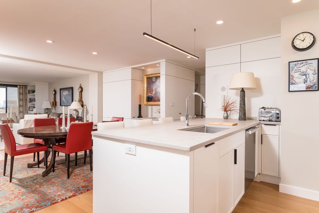 Bright open kitchen with white island, red chairs, and dining area in a modern home