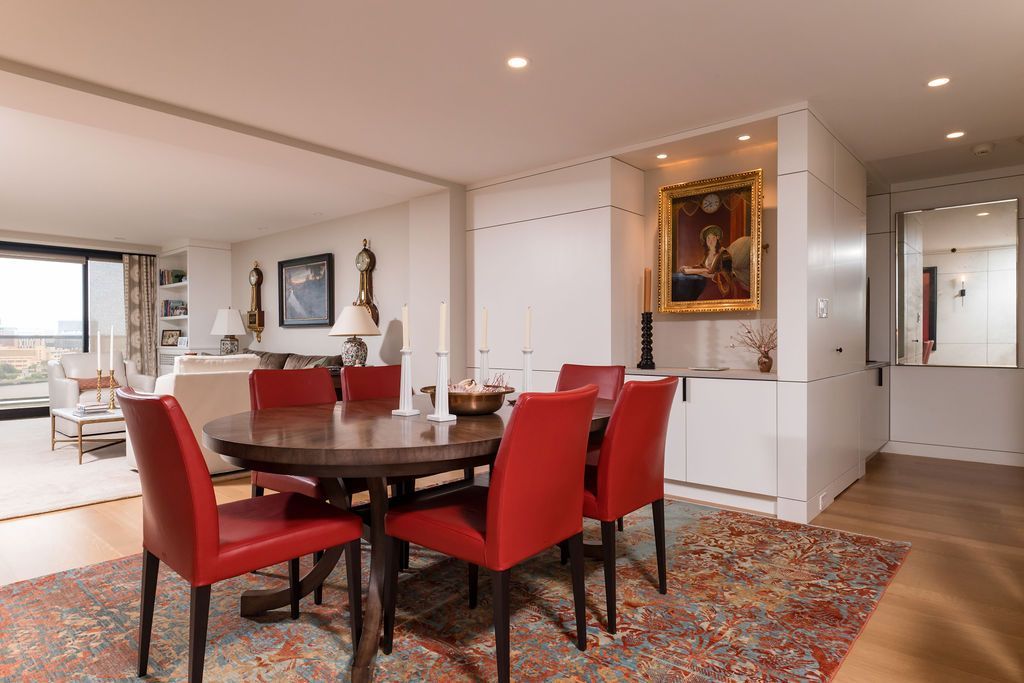 Elegant dining room with red chairs, dark table, patterned rug, and wall art in a bright open home interior