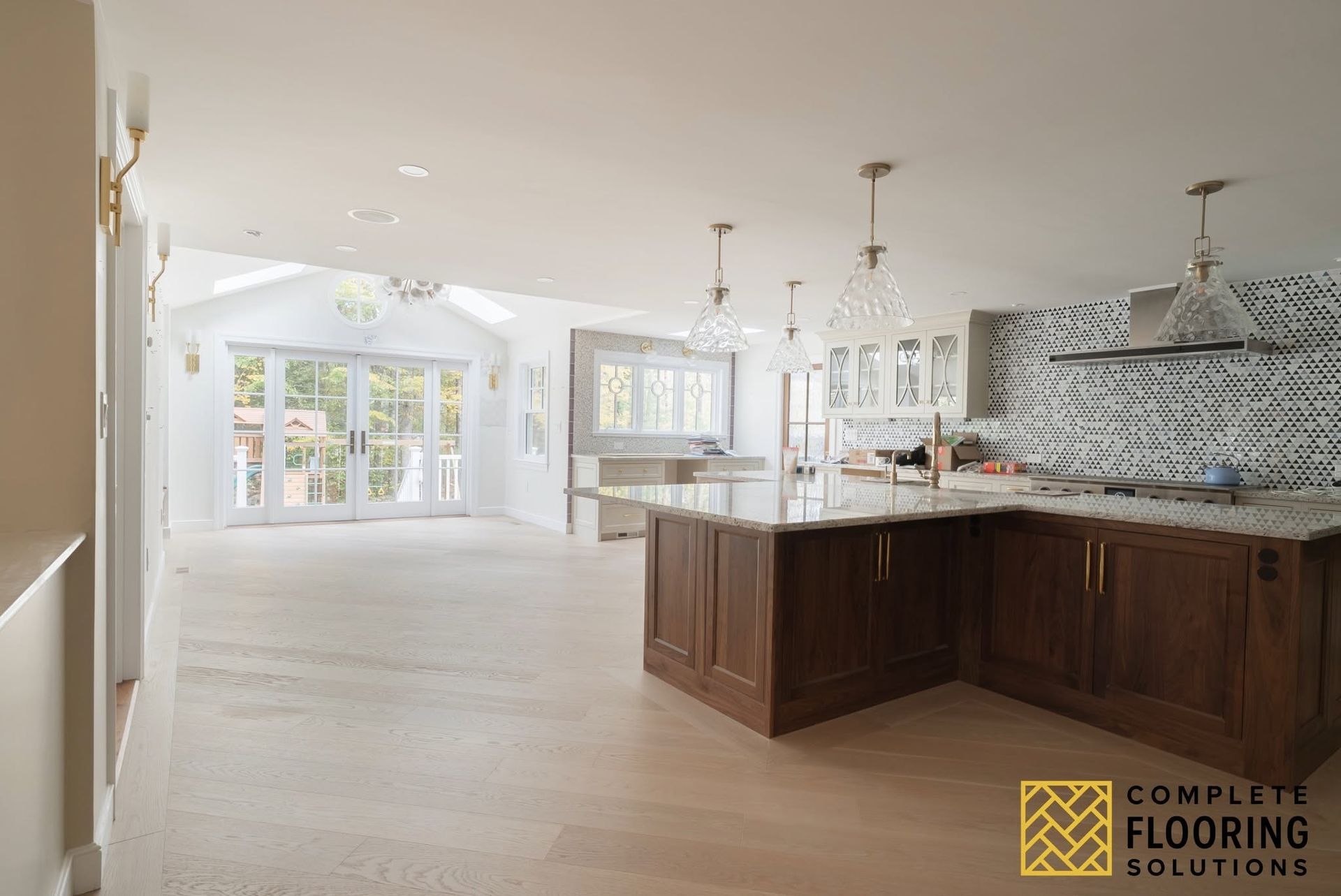 Bright open kitchen with large island, white cabinets, and French doors in a spacious living area