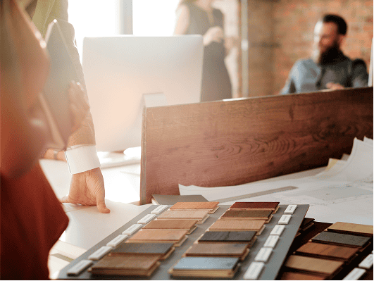 Sample makeup palette on a table with a blurred person and laptop in the background