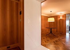 Wood-paneled dining room and hallway with herringbone floor, pendant lamp, and large mirror