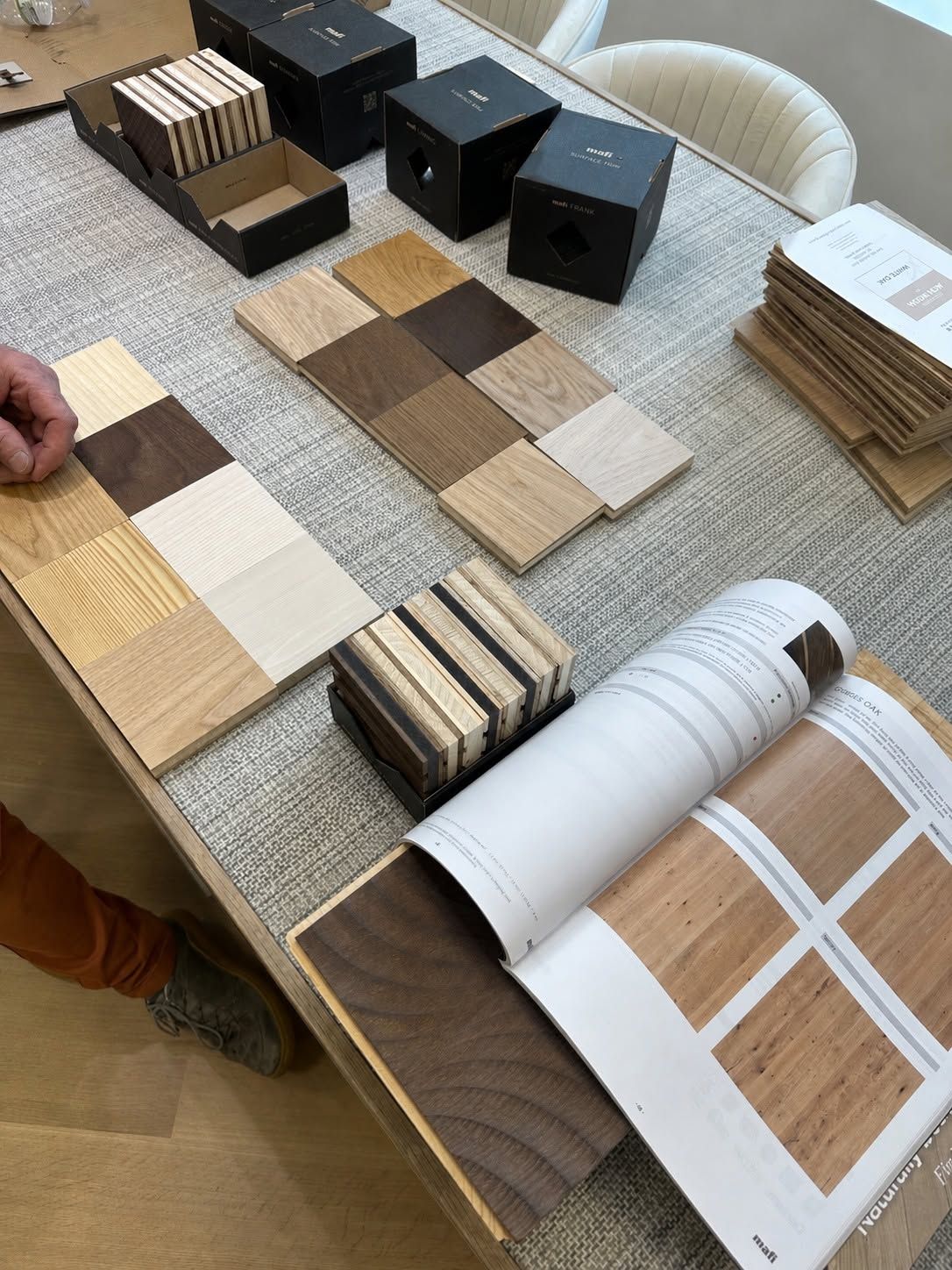 Color swatches, wood samples, and material boards arranged on a table with a catalog open.