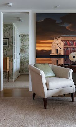 Cozy beige armchair in a neutral bedroom or sitting room with wall art and a mirrored doorway