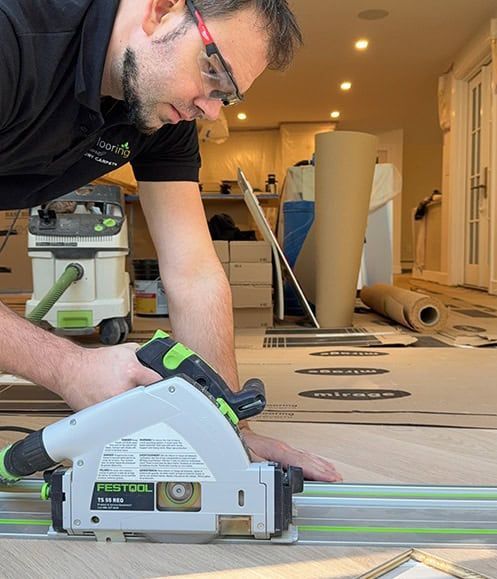 Person using a circular saw to cut large cardboard sheets in a room under renovation.