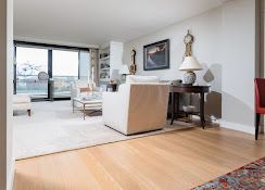 Modern living room with white sofa, side table, and large windows overlooking a balcony