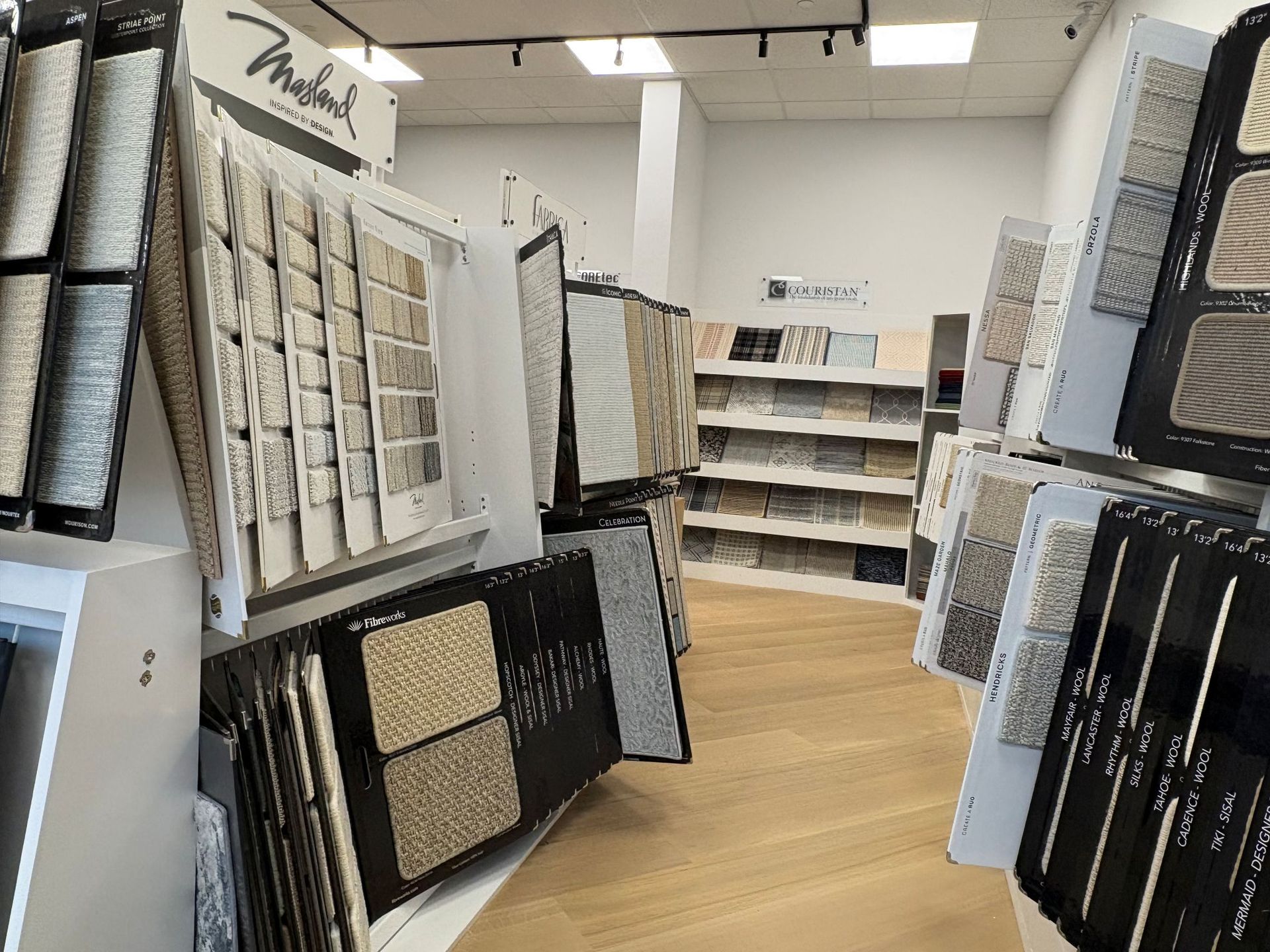 Display of framed artwork and wall decor in a bright retail showroom with wood flooring