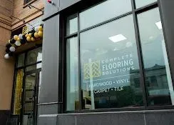 Storefront window for Complete Flooring Solutions, with vinyl flooring and carpet tile signage.