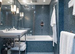 Modern blue-tiled bathroom with sink, bathtub, mirror, and white towels