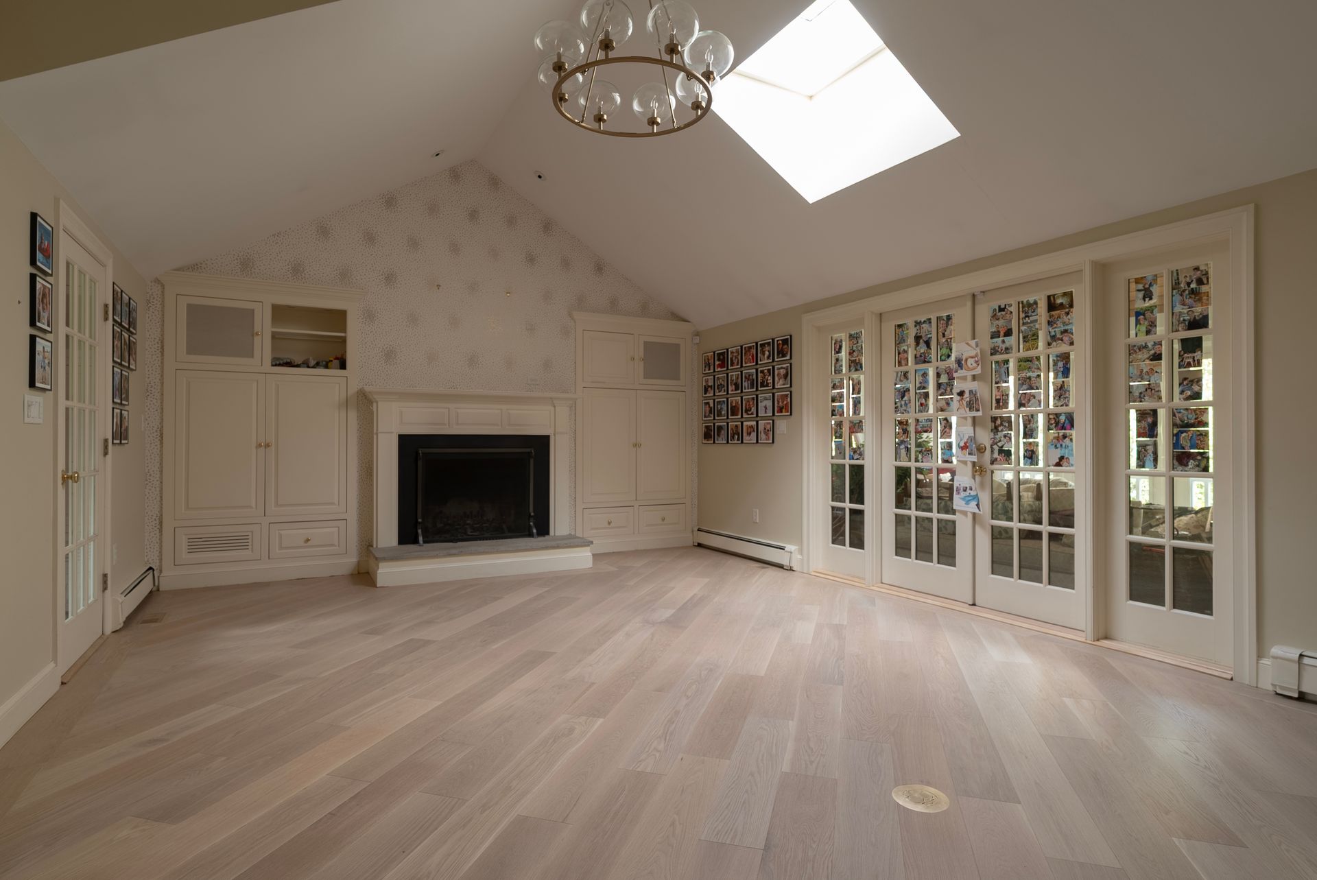 Empty beige living room with fireplace, skylight, and French doors opening to a garden