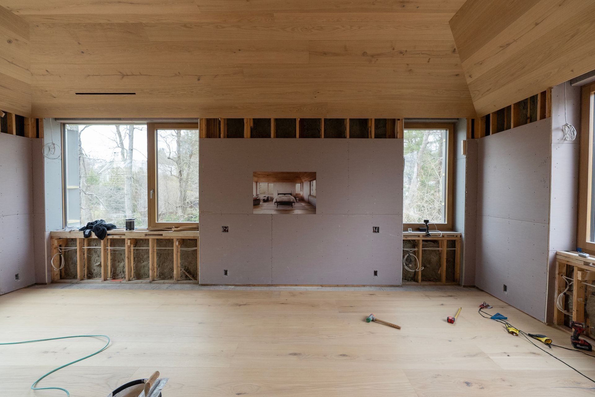 Unfinished room with wood ceiling, exposed wall framing, and large windows during renovation
