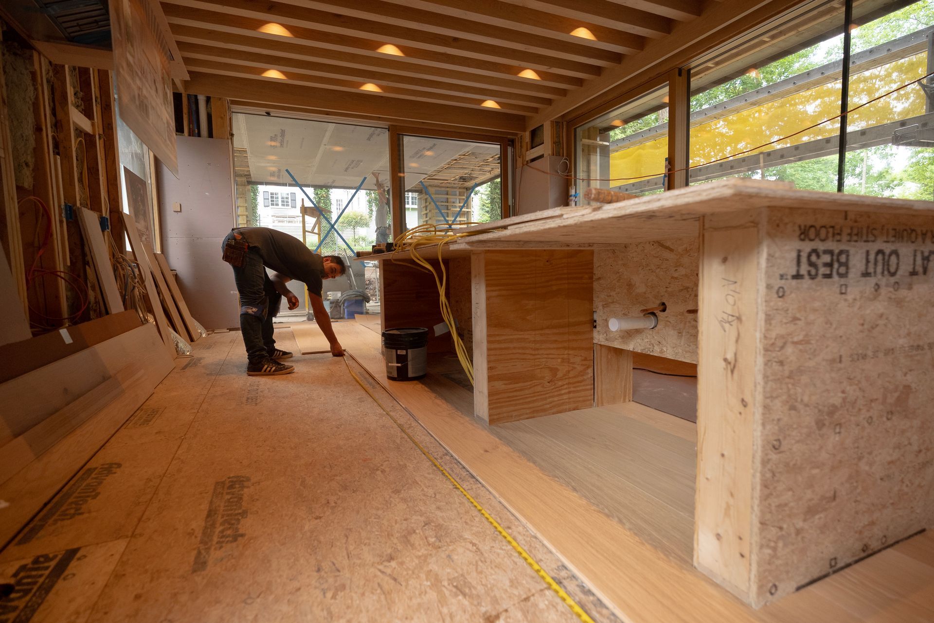 Worker measuring a large wooden cabinet inside a construction site workshop
