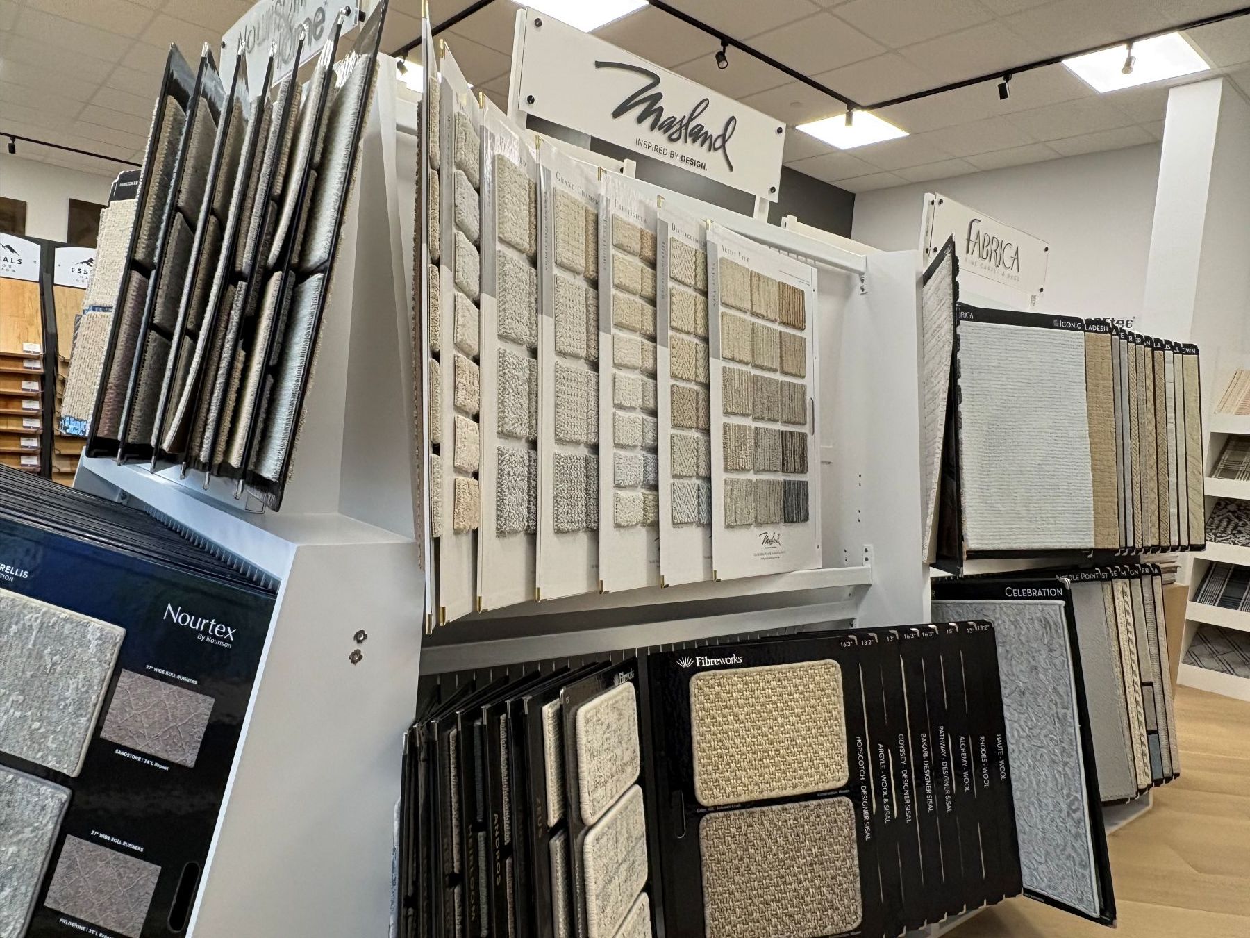 Display of flooring and wall tile samples in a showroom, with white racks and neutral tones.