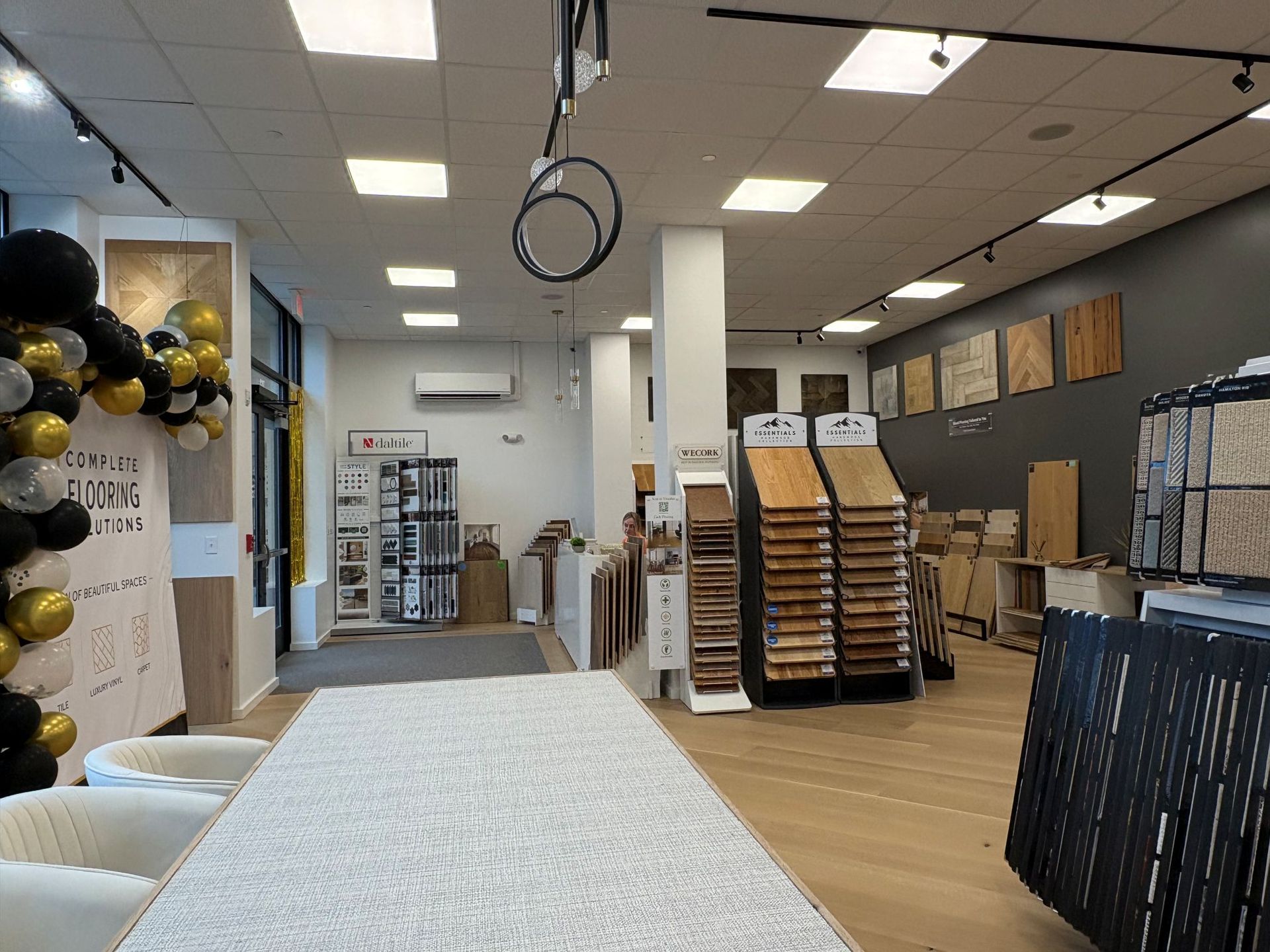Interior of a retail store with white tables, stacked chairs, and black-and-gold balloon decorations near the entrance