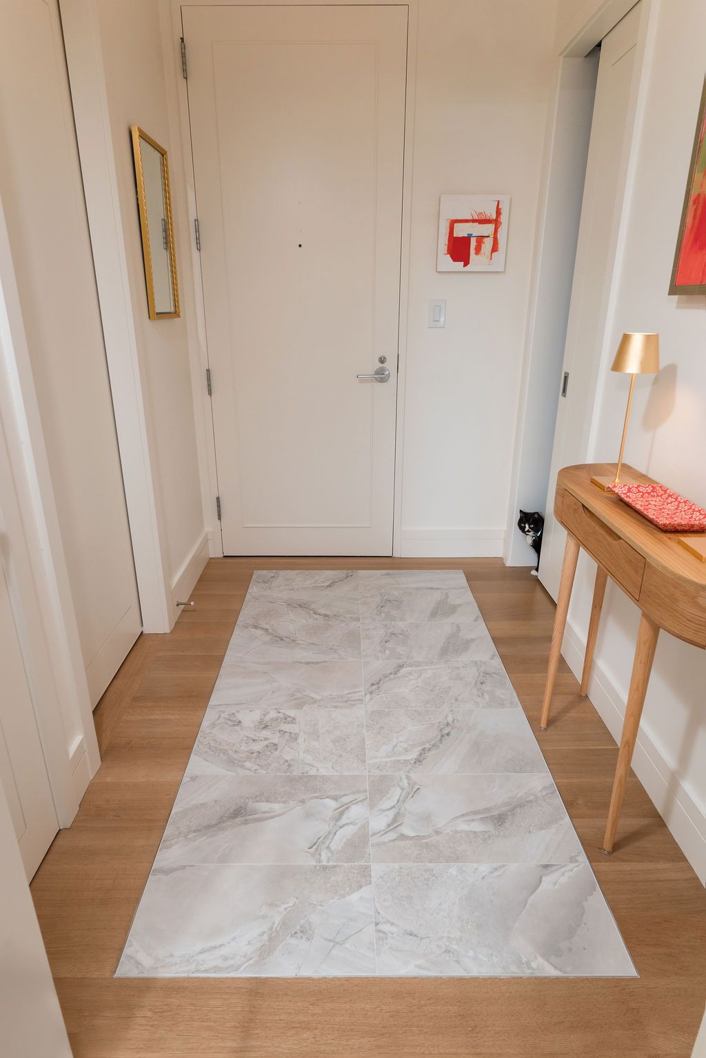 Bright hallway with white doors, a pale rug, and a wooden console table against the wall.