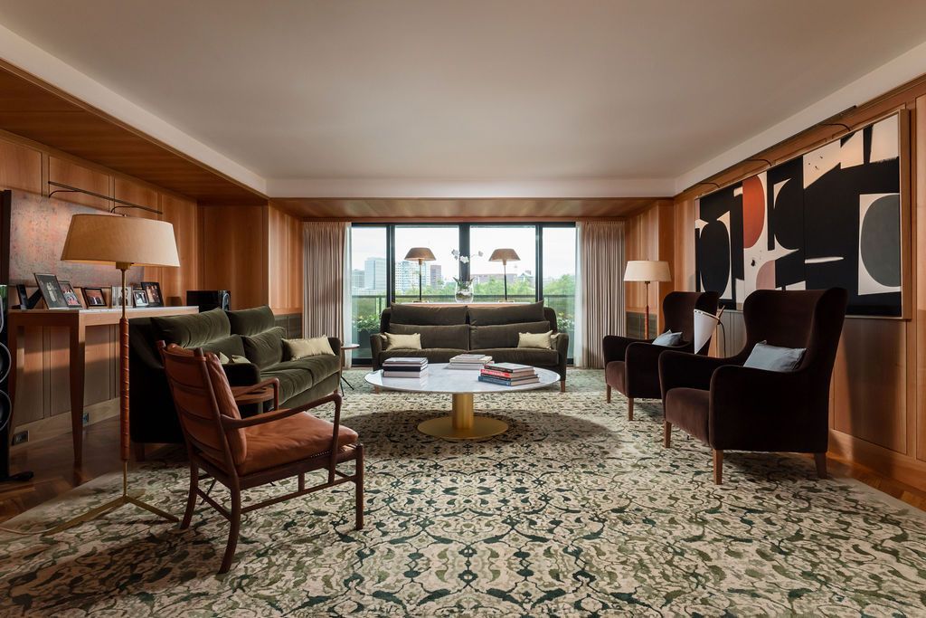 Elegant living room with wood paneling, patterned rug, and large windows overlooking a scenic view
