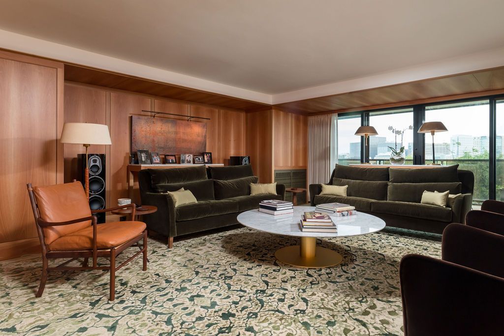 Spacious living room with brown wood paneling, black sofa, round coffee table, and large windows with ocean view