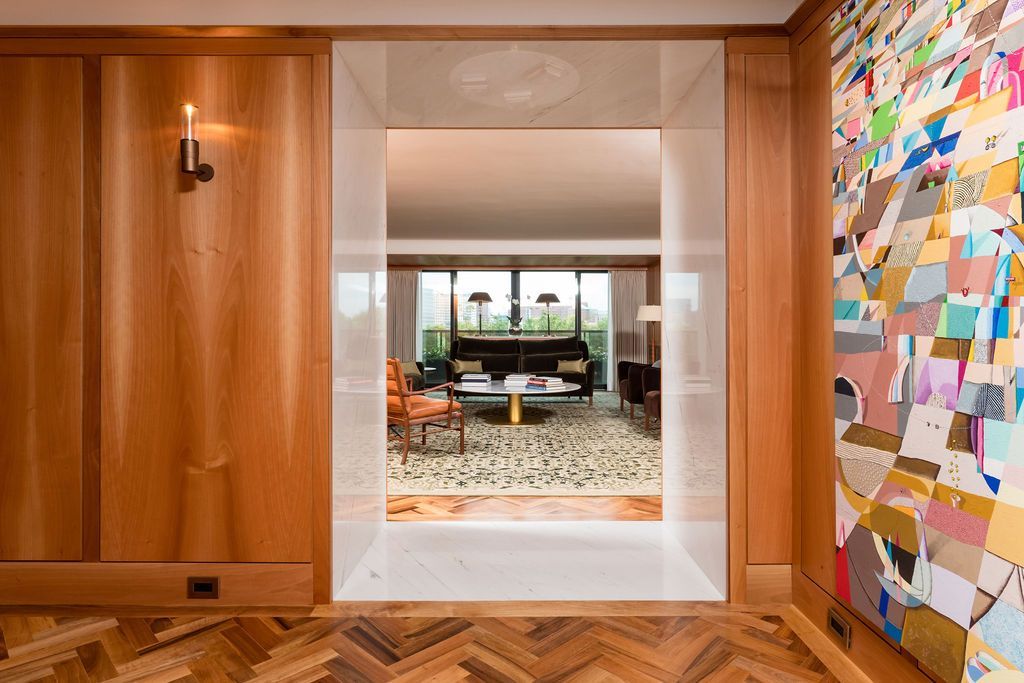 Wood-paneled hallway opening to a bright living room, with a colorful abstract wall on the right.