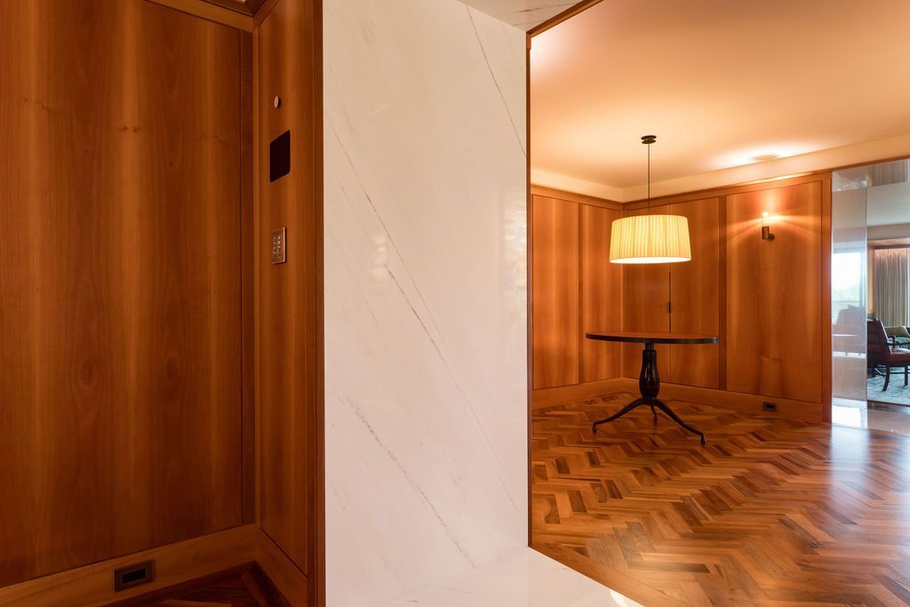 Wood-paneled room with a hanging lamp, herringbone wood floor, and marble entryway.