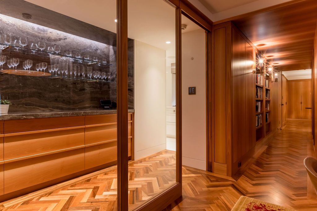 Elegant wood-paneled hallway with warm lighting, mirrored wall, and herringbone parquet floor