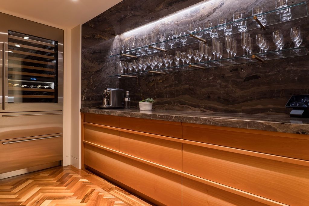 Modern bar interior with hanging glassware, wooden counter, and warm amber lighting