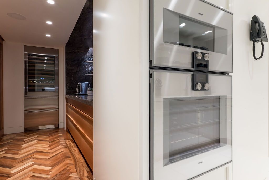 Modern kitchen hallway with built-in white appliances and warm wood flooring