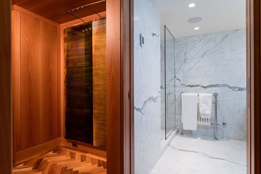 Spa-like shower and sauna area with wood-paneled room beside a marble walk-in shower.