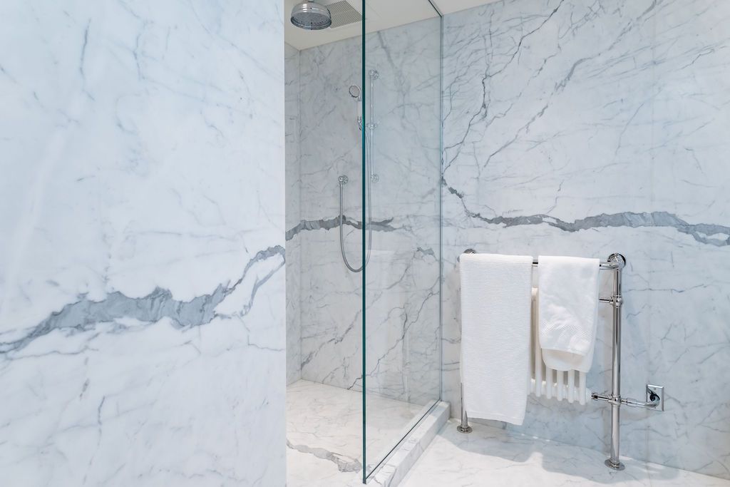 Modern marble bathroom with glass shower and towel rack