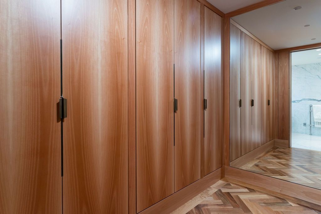 Wood-paneled hallway with built-in wooden doors and a herringbone floor, lit by natural light