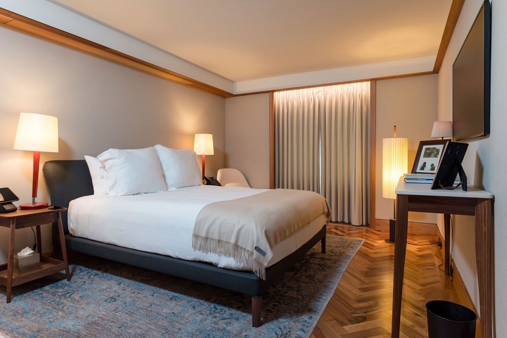 Neat hotel room with a large bed, bedside lamps, a window, and a wooden desk.