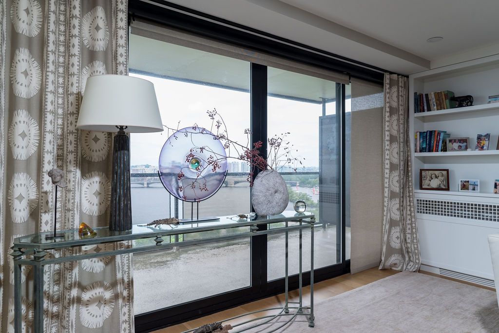 Modern living room with sliding glass doors, glass console table, lamp, rug, and built-in shelves