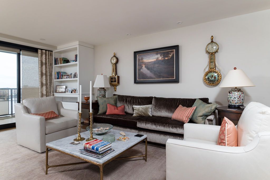 Bright living room with white and gray sofas, a glass coffee table, wall art, and balcony view