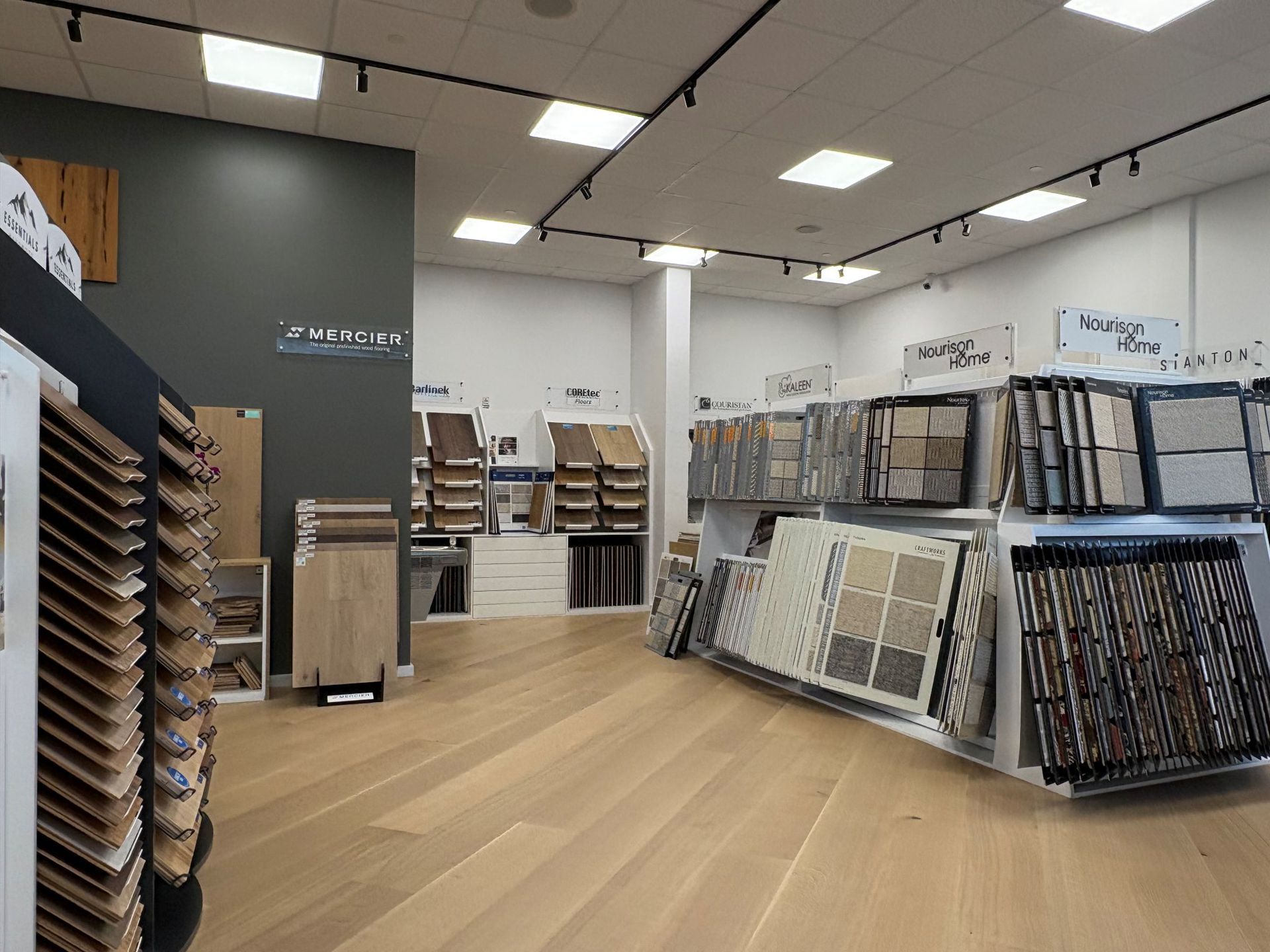 Flooring store showroom with wood plank samples and display racks under bright ceiling lights
