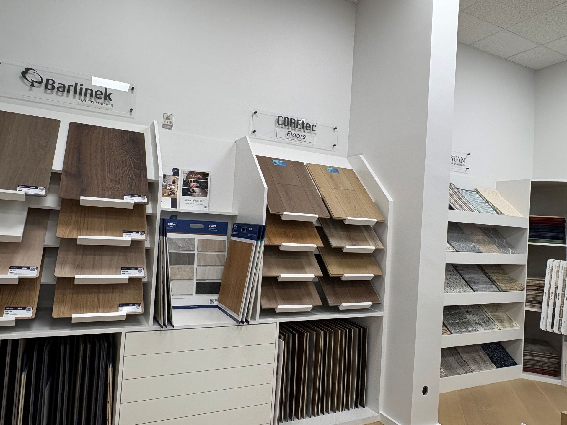 Display of sample flooring and wall materials in a showroom, with shelves of panels and swatches.