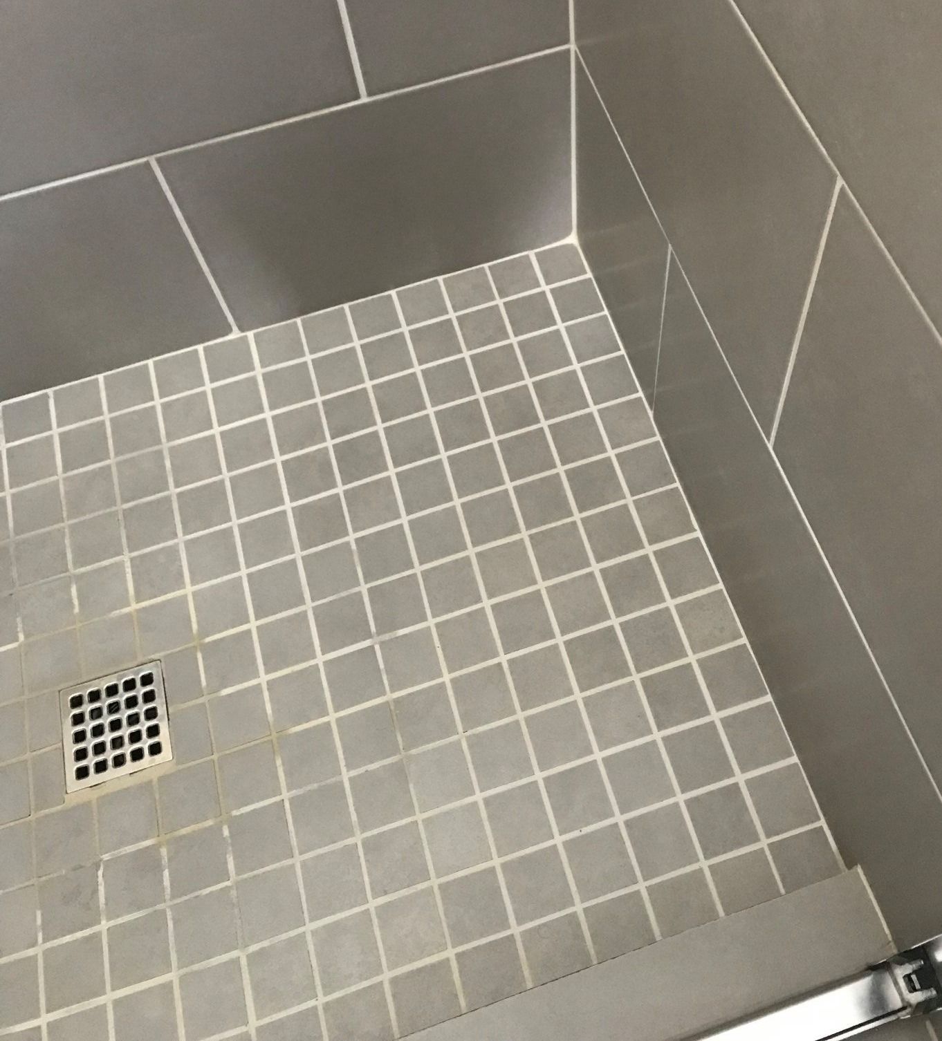 Gray tiled shower floor with a square drain, surrounded by larger gray tiles on the walls.