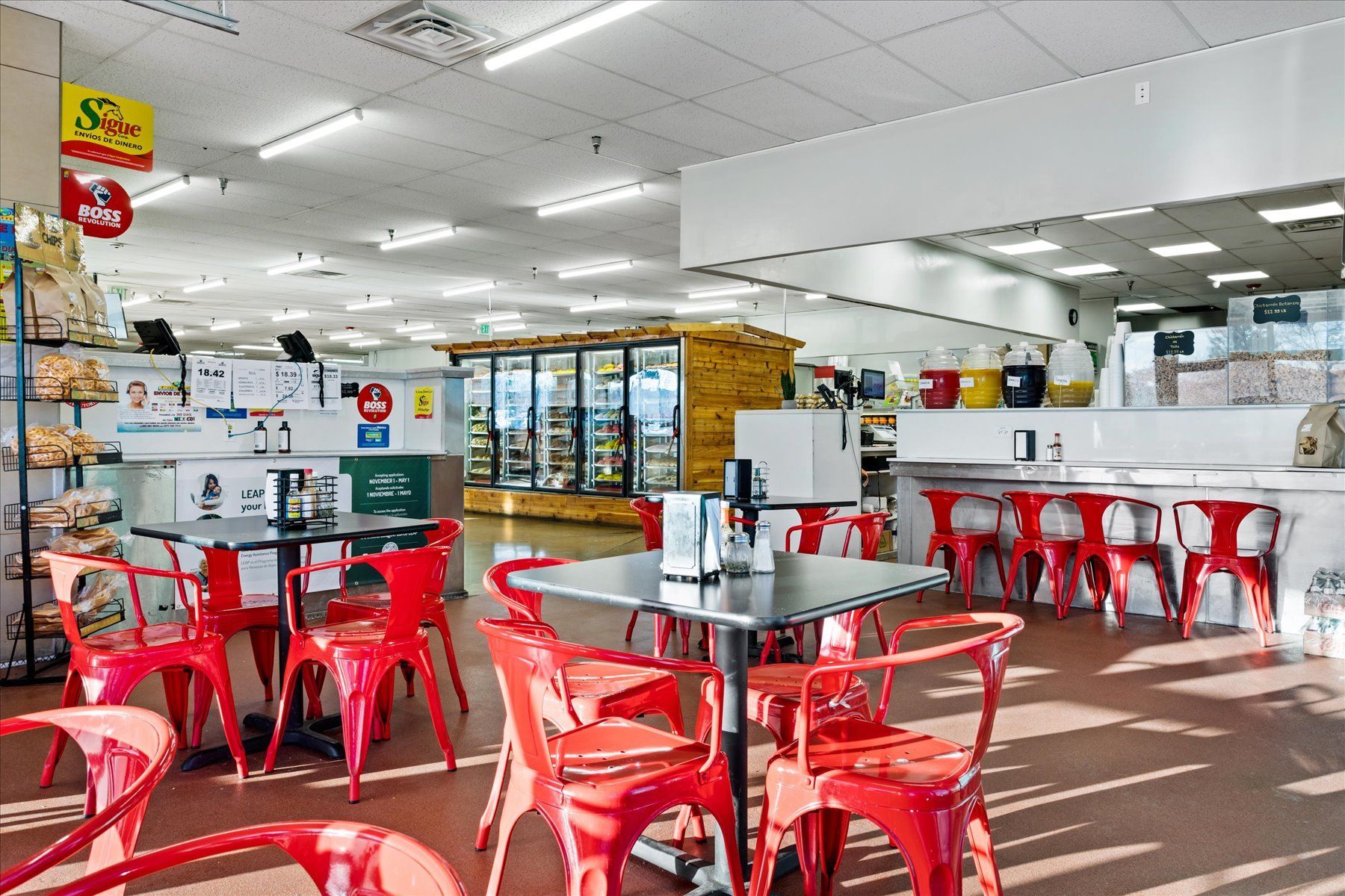 A restaurant with red chairs and tables in a large room.