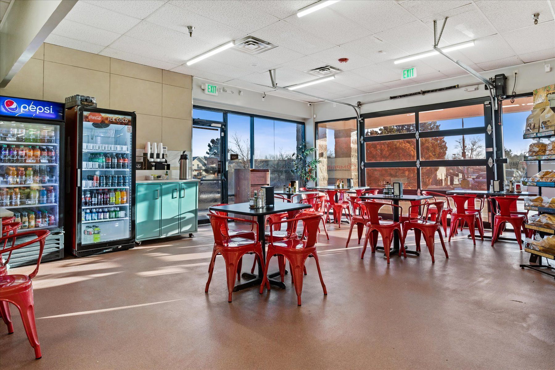 A restaurant with tables and chairs and a pepsi cooler